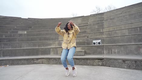 Smiling-black-woman-dancing-on-steps-in-park