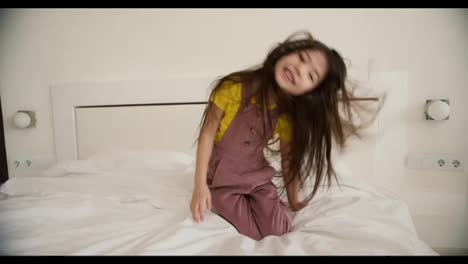 Lovely-asian-looking-listening-using-headphones-on-the-bed-and-funny-dancing