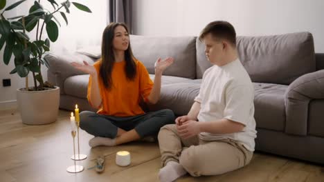 Portrait-of-a-woman-assisting-guy-with-down-syndrome-doing-in-meditating-at-home