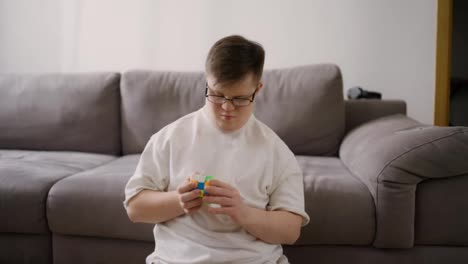 Mann-Mit-Down-Syndrom-Sitzt-Zu-Hause-Auf-Dem-Boden-Und-Spielt-Mit-Rubik-Cube