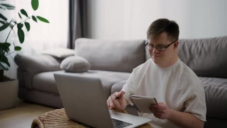 Down-syndrome-young-adult-man-sitting-at-home,-using-laptop-for-learning