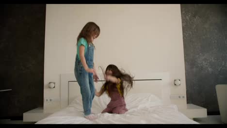 Zwei-Kleine-Schwestern-Haben-Spaß-Daran,-Auf-Das-Bett-Im-Schlafzimmer-Ihrer-Eltern-Zu-Springen