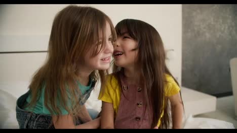 Lovely-little-cute-girl-combing-the-hair-of-her-older-sister,-having-fun-and-whispering-gossips-for-fun