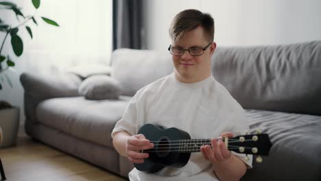 Portrait-of-a-Down-syndrome-boy-having-fun-while-playing-ukulele-at-home