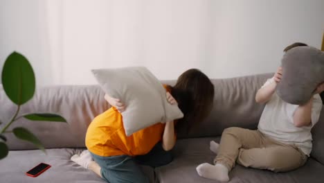 Sister-brother-fight-on-sofa-with-pillows,-a-woman-and-a-guy-with-Down-syndrome