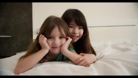Two-happy-small-kids-in-bedroom,-smiling-and-looking-to-the-camera