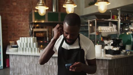 Black-person---a-waiter-in-a-doner-market-puts-on-wireless-headphones-and-listens-to-music