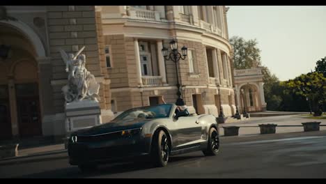 A-beautiful-dark-gray-Cabriolet-makes-a-turn-in-front-of-a-building-with-amazing-Renaissance-architecture
