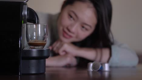 Asiatische-Frau-Erwägt-Die-Zubereitung-Eines-Heißgetränks-In-Einer-Kapselkaffeemaschine