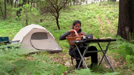 Woman-putting-mushroom-on-table-in-forest-with-tent