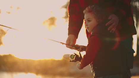cute-little-boy-is-fishing-father-or-grandpa-is-helping-child-active-rest-in-nature-catch-fish-in-lake