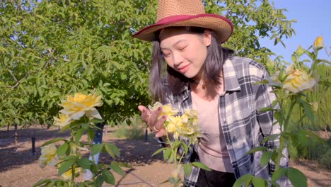 Cheerful-Asian-woman-in-lush-garden-with-roses-in-countryside