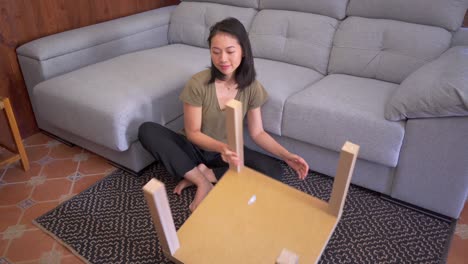 Asiatische-Frau-Baut-Tisch-Im-Wohnzimmer-Zusammen