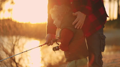 little-boy-anf-his-father-are-fishing-together-on-river-or-lake-shore-in-sunset-time