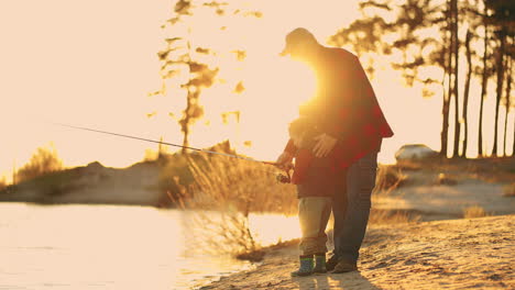 beautiful-sunset-on-river-shore-old-fisherman-and-his-little-son-or-grandson-are-fishing-together