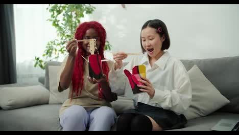 Diverse-female-friends-eating-together-at-home-using-chopsticks