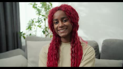 Portrait-of-smiling-African-american-woman-with-red-stylish-hair-at-home
