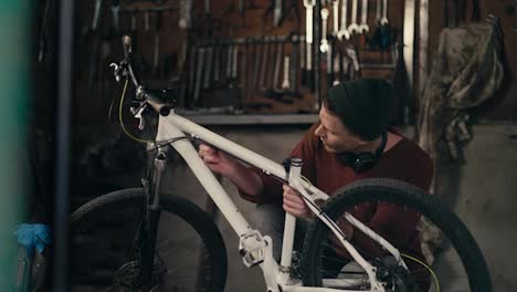 Mastering-the-Details:-Skilled-Mechanic-in-Brown-Sweater-Inspecting-White-Bike-in-Workshop