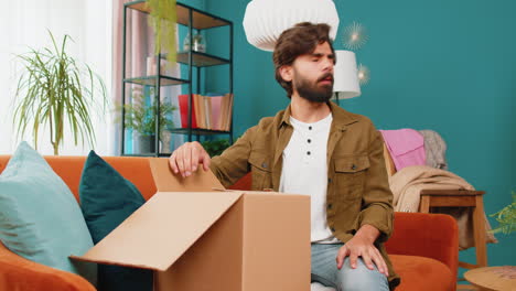 Angry-dissatisfied-shopper-middle-eastern-man-unpacking-parcel-feeling-upset-confused-wrong-delivery
