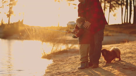 little-boy-father-and-dog-are-resting-on-shore-of-lake-in-sunset-child-is-learning-to-catch-fish