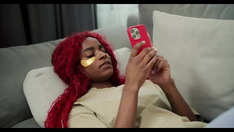 Young-beautiful-african-woman-with-eye-patches-using-mobile,-typing-message