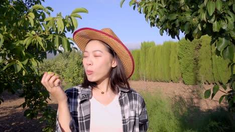 Cheerful-Asian-woman-eating-ripe-apple-in-garden-in-countryside
