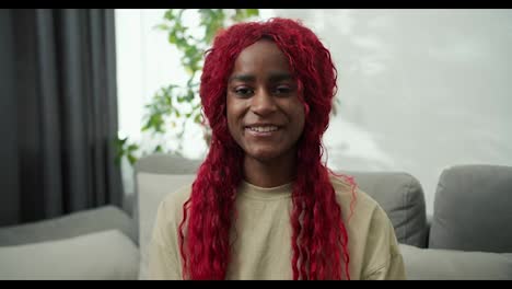 Porträt-Einer-Lächelnden-Afroamerikanischen-Frau-Mit-Roten,-Stilvollen-Haaren-Zu-Hause,-Die-In-Die-Kamera-Schaut-Und-Lacht