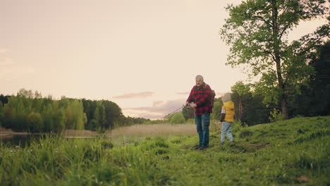 fishing-on-shore-of-beautiful-forest-lake-grandfather-and-his-grandson-are-spending-time-together