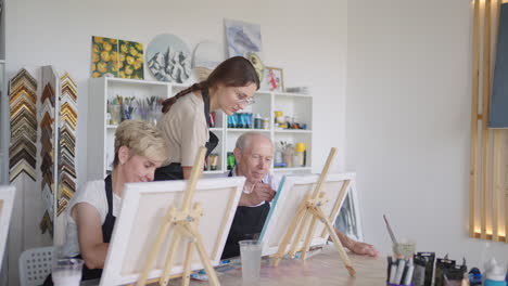 Side-view-of-a-happy-senior-people-smiling-while-drawing-as-a-recreational-activity-or-therapy-in-paint-class-together-with-the-group-of-retired-women-and-men