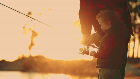 little-boy-is-spending-time-with-father-or-grandfather-on-river-shore-or-lake-coast-in-sunset