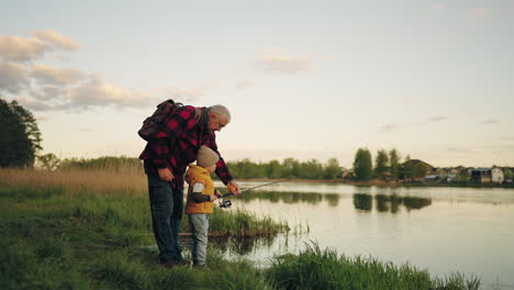 old-man-and-his-grandson-are-fishing-on-coast-of-beautiful-pond-little-boy-and-his-grandfather