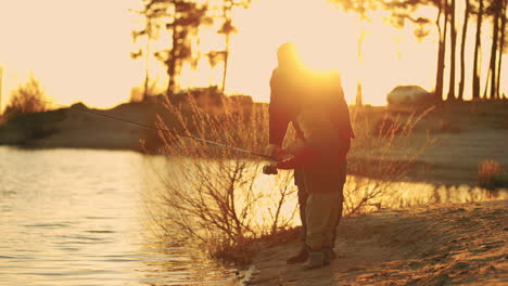 rest-on-shore-of-lake-in-sunset-old-fisherman-and-little-grandson-are-fishing-in-river-happy-childhood
