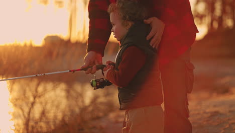curious-little-boy-is-helping-father-to-fish-grandfather-and-grandson-are-fishing-together-in-sunset