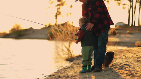 idyllic-family-scene-on-coast-of-river-or-lake-in-sunset-time-little-boy-and-father-are-fishing