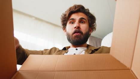 Happy-arabian-man-shopper-unpacking-cardboard-box-delivery-parcel-online-shopping-purchase-at-home