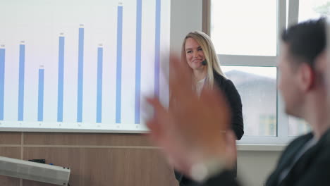 female-marketing-specialist-is-speaking-on-business-meeting-in-big-company-smiling-against-chart