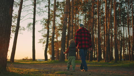little-boy-and-his-father-or-granddad-are-walking-in-pinery-in-morning-or-sunset-going-to-fishing