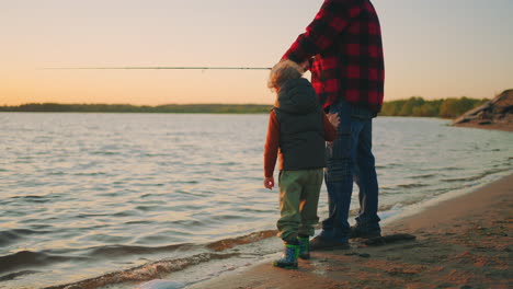 calm-family-rest-on-river-shore-father-and-little-son-are-fishing-beautiful-sunset-in-autumn-or-spring-evening