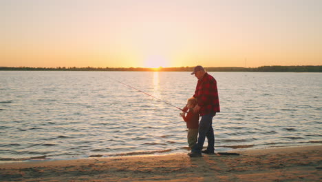 happy-joint-pastime-of-grandpa-and-grandson-in-nature-old-man-and-little-boy-are-fishing-on-river-shore