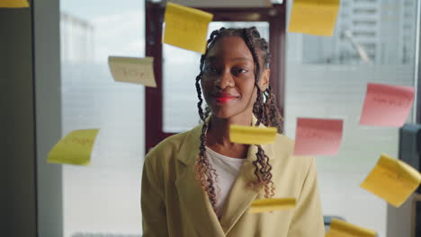 Smalling-African-american-business-woman-using-sticky-notes-brainstorming-problem-solving-strategy-on-glass-whiteboard-leader-woman-showing-solution-for-project-deadline-in-office.