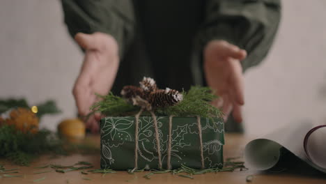 A-Christmas-present-moves-a-woman's-hands-into-the-camera.-green-Packaged-Gift-Woman-Moves-Into-Camera-After-Packing-and-Decorating.-Slow-motion
