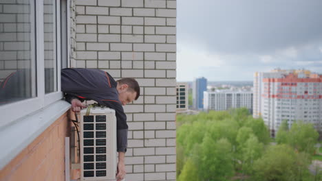 A-man-at-high-altitude-installs-air-conditioning.-Installation-of-the-external-unit-of-the-Air-Conditioning-System.-Creating-a-microclimate-in-the-apartment