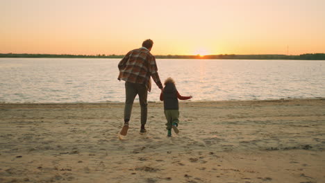 dad-and-son-are-holding-hands-and-running-to-river-in-sunset-time-happy-family-weeknd