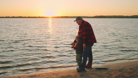 fishing-on-river-or-lake-shore-granddad-and-grandson-are-catching-fish-by-fishing-rod