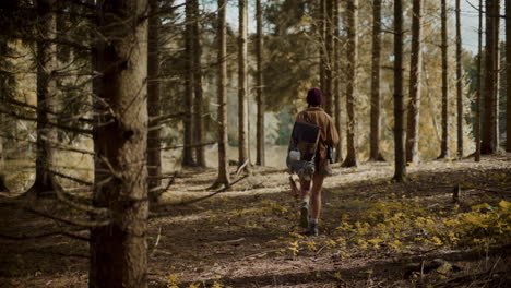Young-woman-with-backpack-exploring-amidst-trees