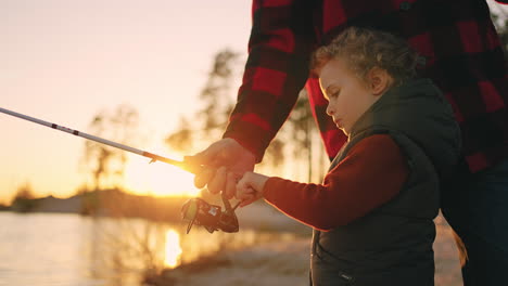 curious-little-boy-is-learning-to-catch-fish-by-fishing-rod-father-or-grandpa-is-helping
