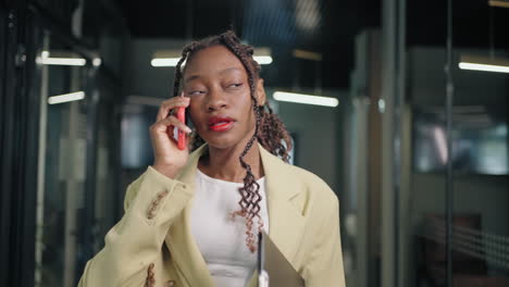 Retrato-De-Una-Mujer-De-Negocios-Negra-Hablando-Por-Teléfono-En-El-Pasillo-De-Un-Centro-De-Negocios