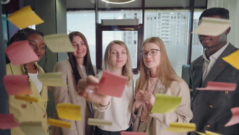 portrait-of-multiethnic-team-of-office-workers-through-glass-wall-with-post-it-notes-in-office