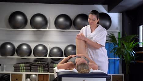 Delight-female-physiotherapist-massaging-leg-of-crop-woman