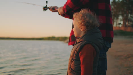 curious-toddler-is-viewing-nature-when-his-father-is-fishing-happy-family-in-nature-in-sunset